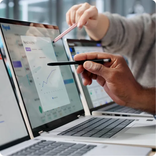 Two people annotating analytics charts on a laptop screen with styluses